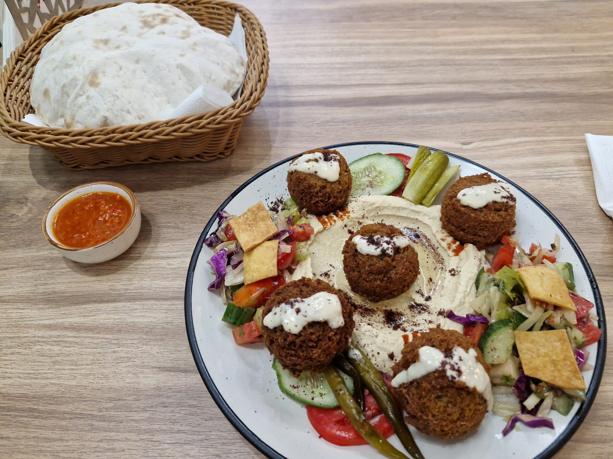 Falafel on hummus with salad, pickles and flatbread