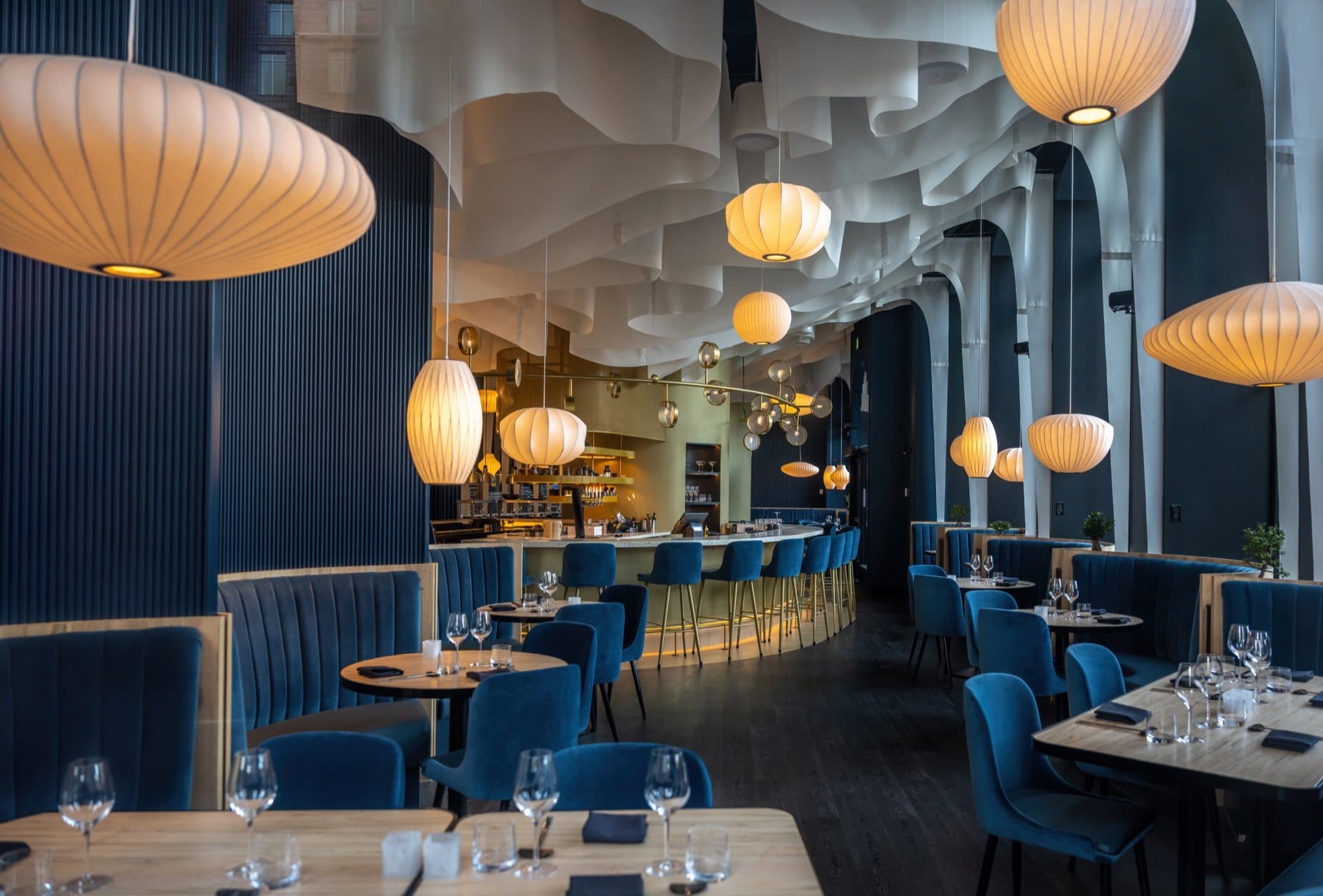 Brasserie dining room with blue banquettes and paper lanterns